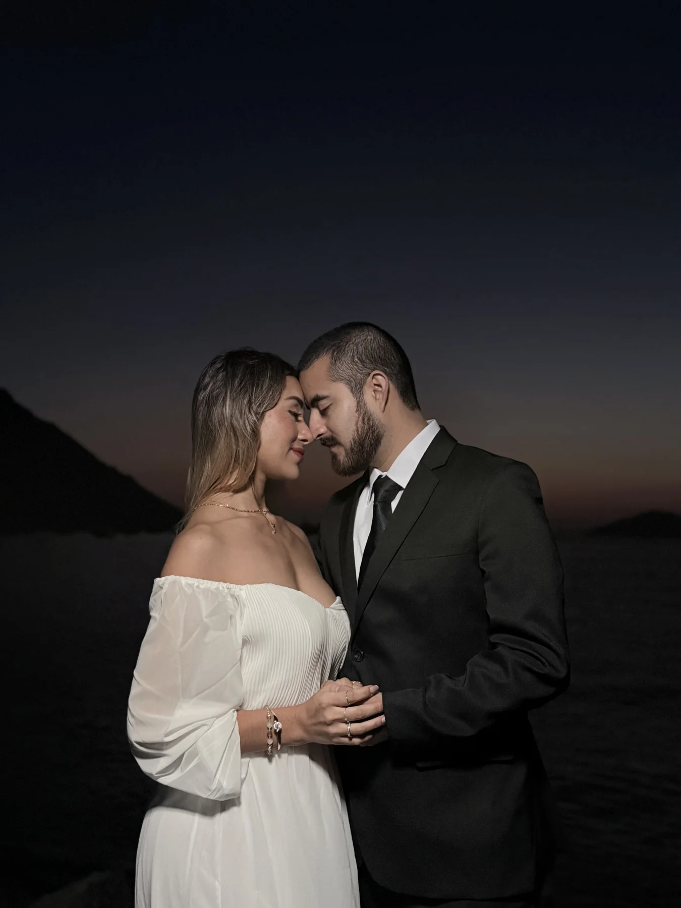 Pareja de novios abrazada al caer la noche