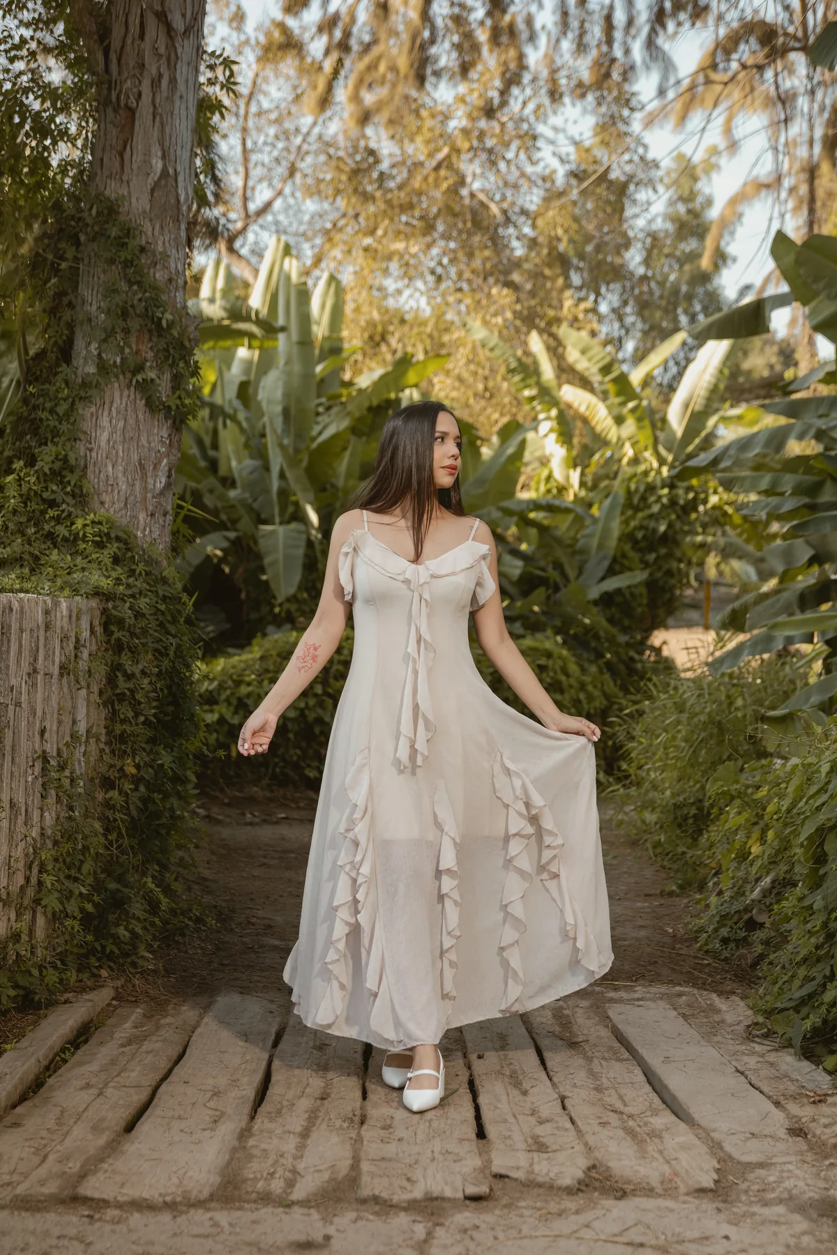 Retrato con vestido claro sobre un sendero de madera entre vegetación