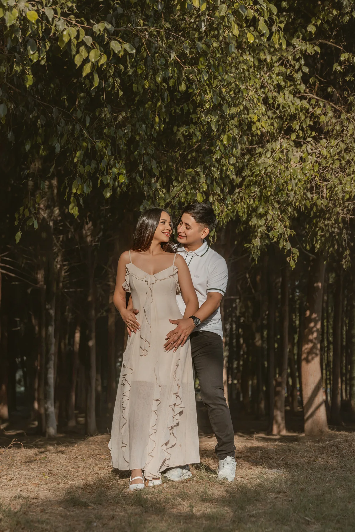 Retrato de cuerpo entero de la pareja abrazada bajo el follaje