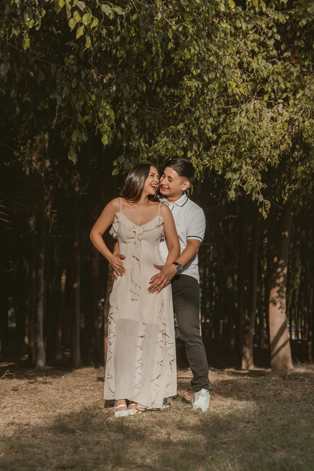 Un beso en la mejilla durante el retrato de pareja entre árboles
